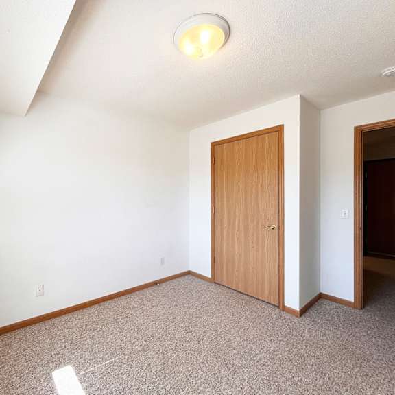 a room with a carpeted floor and a wooden door.