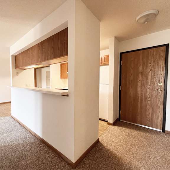 a white kitchen with a brown counter top and a brown door.