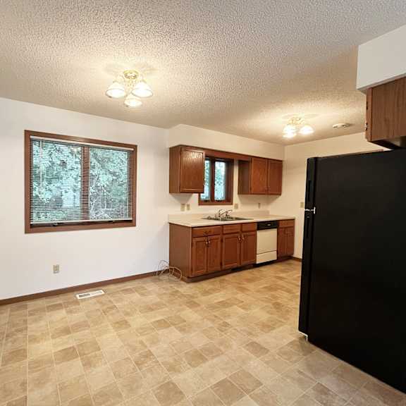 a kitchen with a black refrigerator and brown cabinets.