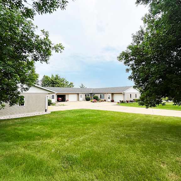 a house with a grey roof and a white garage door is surrounded by a green lawn.