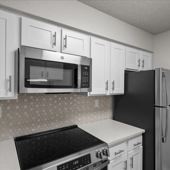 Thumbnail 4 of 9 a kitchen with white cabinets and a stove and a refrigerator