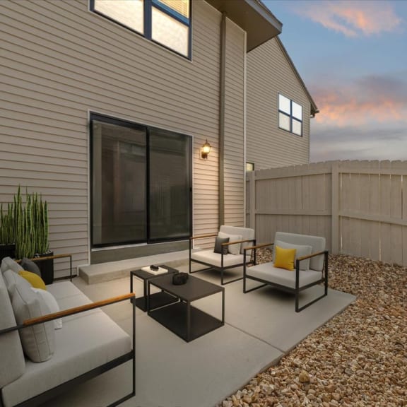 Thumbnail 10 of 10 a patio with a couch and chairs in front of a house