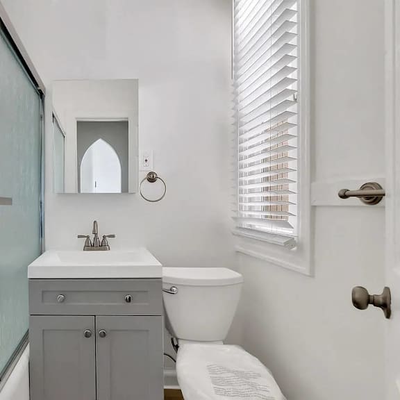 a bathroom with a toilet, sink, and mirror.