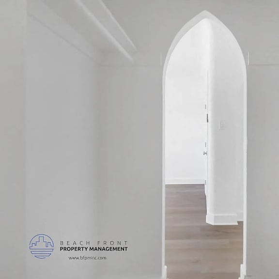 a white hallway with a wooden floor and a white door.