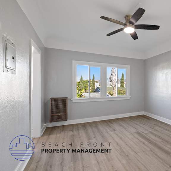 an empty living room with a ceiling fan and a window