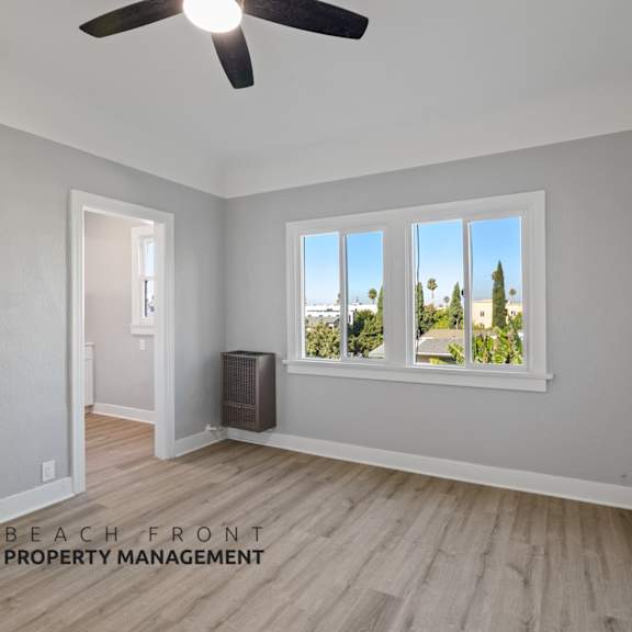 an empty living room with a window and a ceiling fan