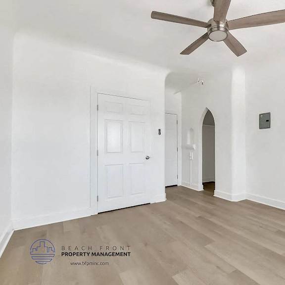 a spacious room with a ceiling fan and light switches on the wall.