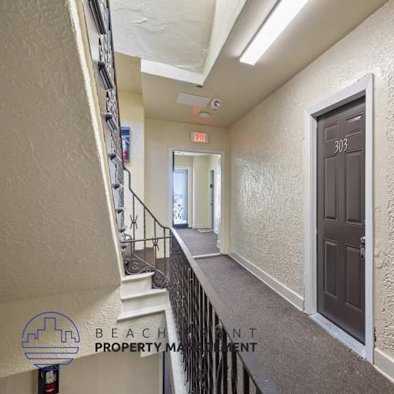 the upstairs hallway of a building with a brown door and stairs