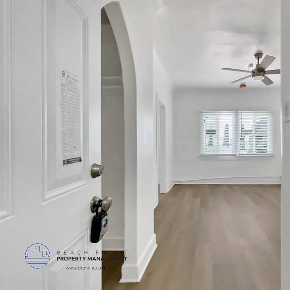 a white door with a keypad lock is on the left and a fan is on the ceiling.
