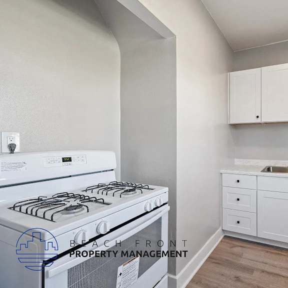 a kitchen with a stove, sink, and cabinets.