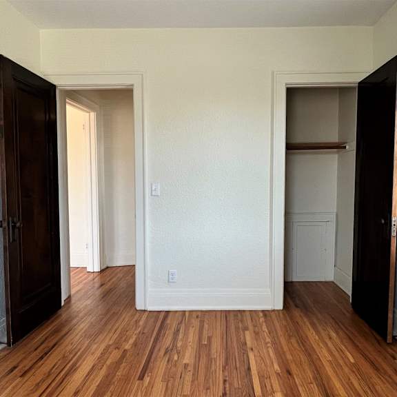 a bedroom with hardwood floors and white walls