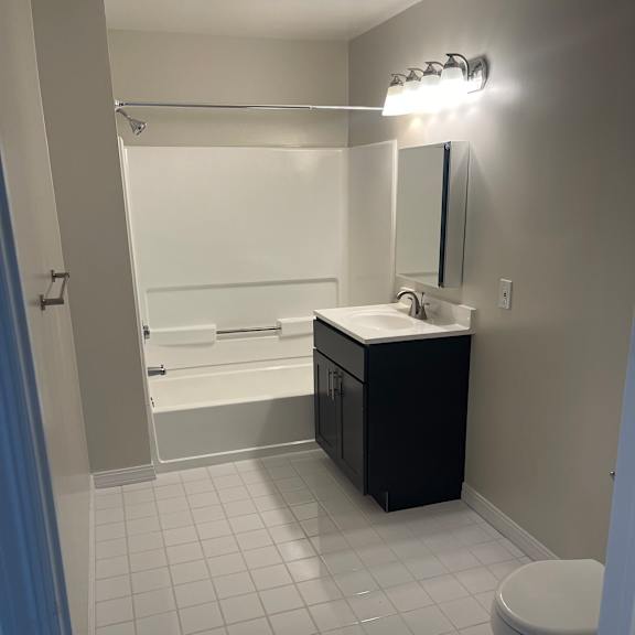 a bathroom with a white tiled wall and a white toilet.
