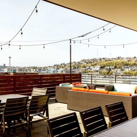 a rooftop patio with tables and chairs and a view of the city