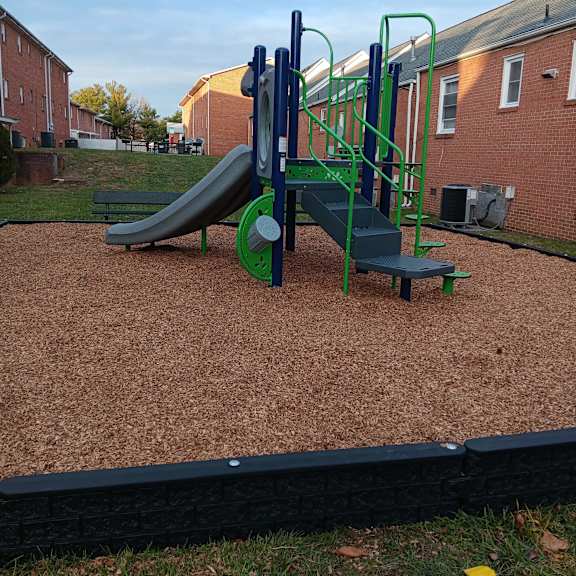 A playground with a green slide and a green and blue climbing frame.