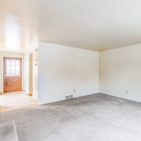 a room with a carpeted floor and a door on the left side.