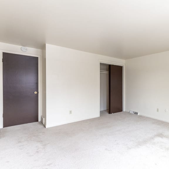 a room with a white ceiling and carpeted floor with two doors.