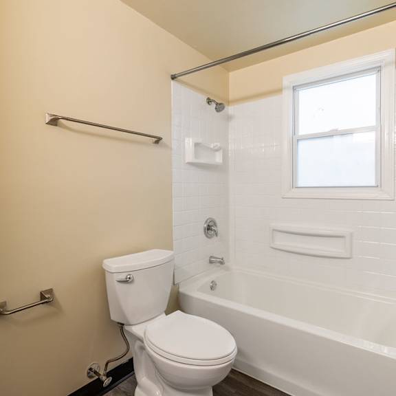 a white toilet sits next to a white bathtub in a bathroom.