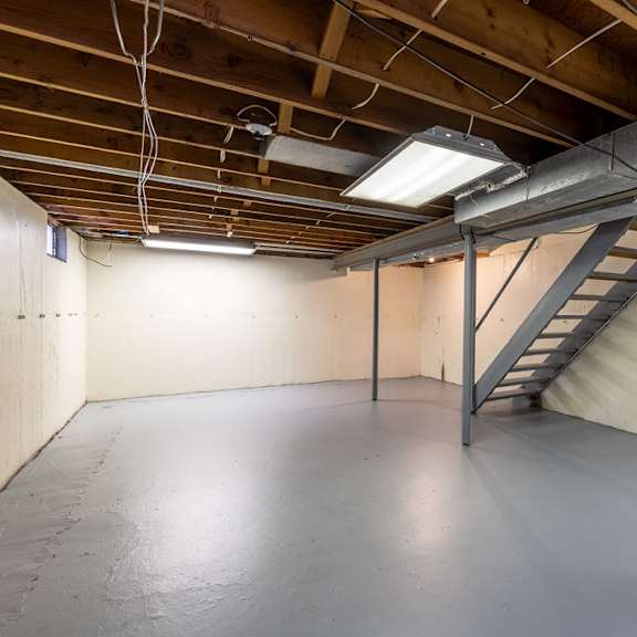 a spacious attic room with a staircase and exposed wooden beams.