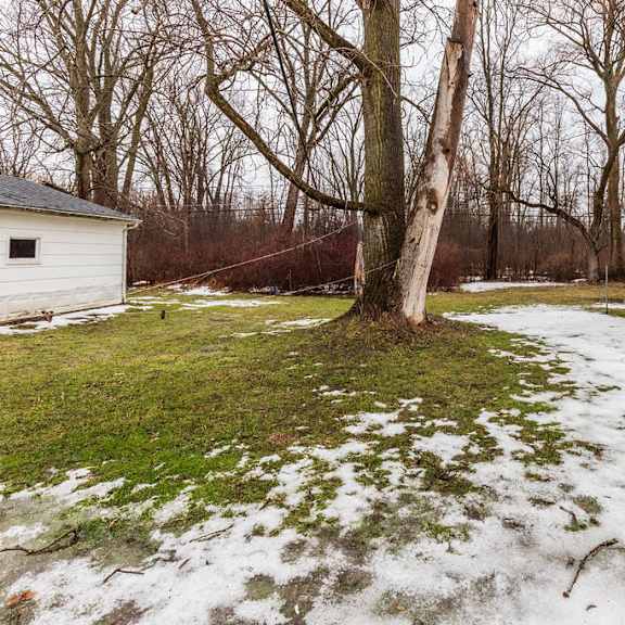 a white shed sits in a snowy field with a tree in the background.