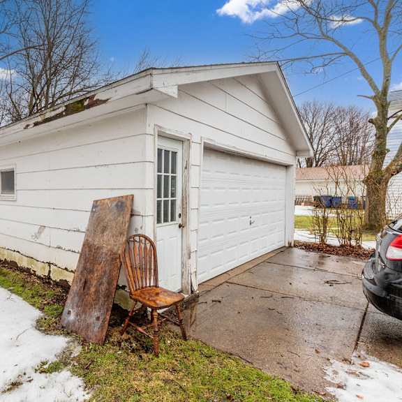 a small white house with a chair and a door.