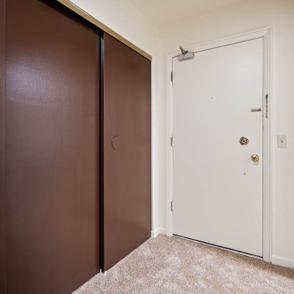 a white door with a gold handle is in a room with brown walls.