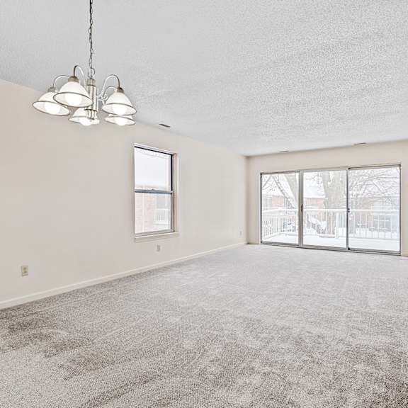 a room with a grey carpet and a window overlooking a snowy landscape.