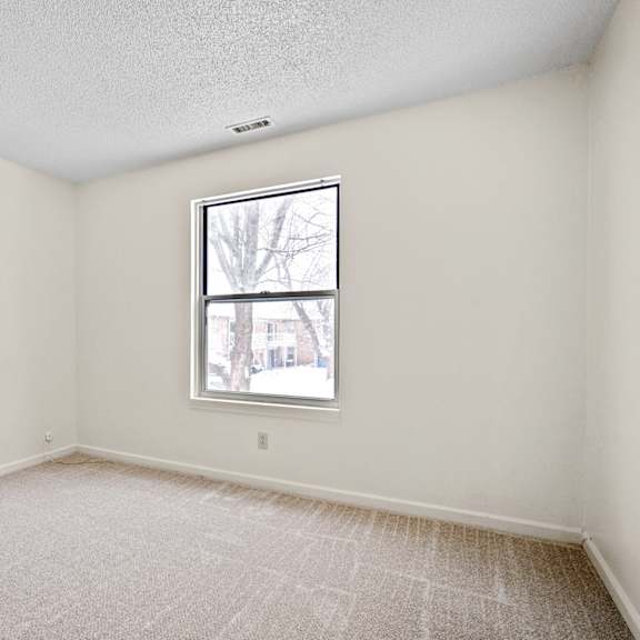 a room with a window and carpeted floor.