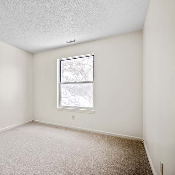 a room with a window and carpeted floor.