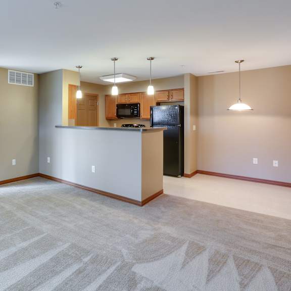 the living room and kitchen of an empty house with the door open