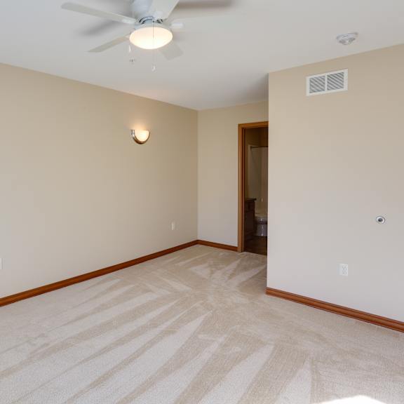 a empty living room with a ceiling fan and a white wall