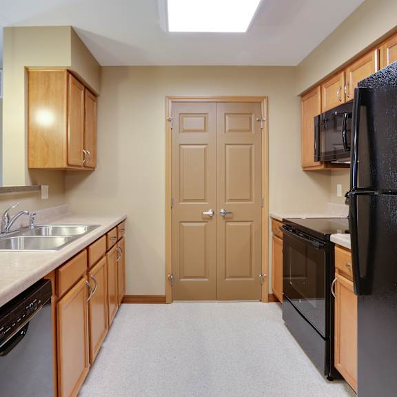 an empty kitchen with a black refrigerator and a sink