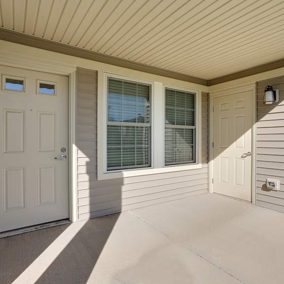 the front porch of a home with a white door