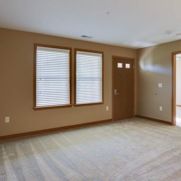 an empty living room with a door and windows