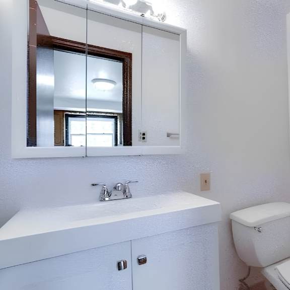 a white bathroom with a toilet, sink, and mirror.
