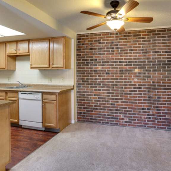 a kitchen with a brick wall and wooden cabinets