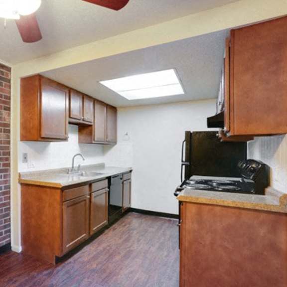a kitchen with a brick wall and wooden cabinets