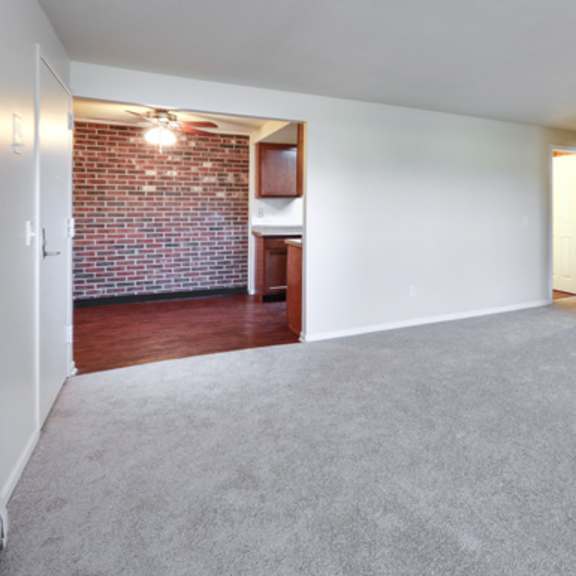an empty living room with a brick wall