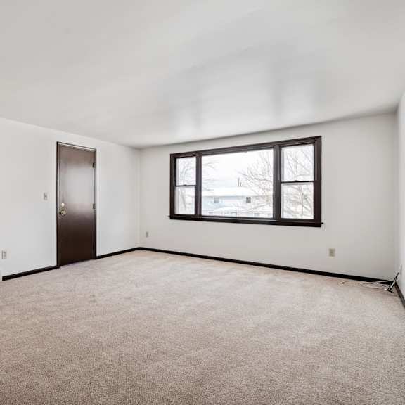 a large, empty room with a carpeted floor and a window.
