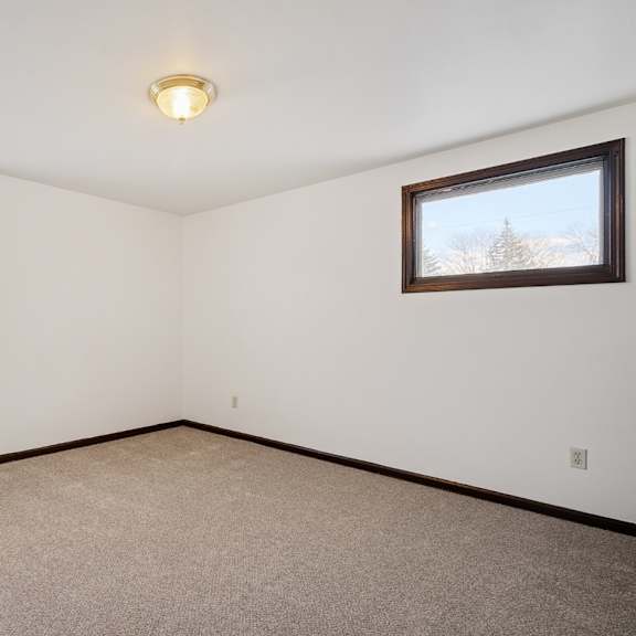 a room with carpeted floor, two windows, and a ceiling light.