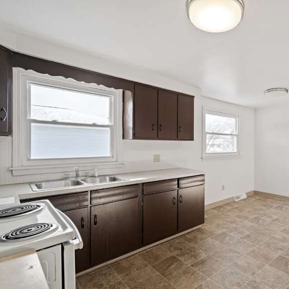 a kitchen with brown cabinets and a tiled floor.