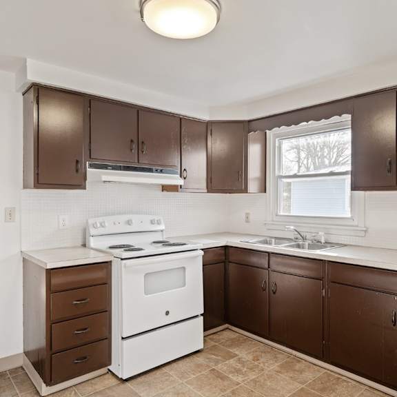 a kitchen with brown cabinets and a white stove top oven.
