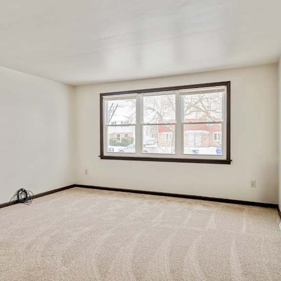 a room with a carpeted floor and a window showing a view of a street.