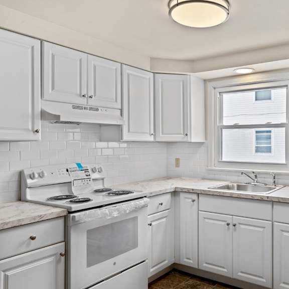 a kitchen with white cabinets and a marble countertop.