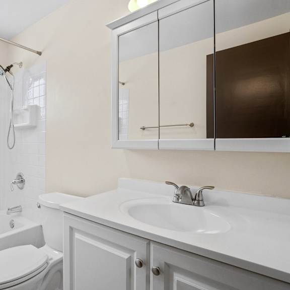 a white bathroom with a toilet, sink, and shower.