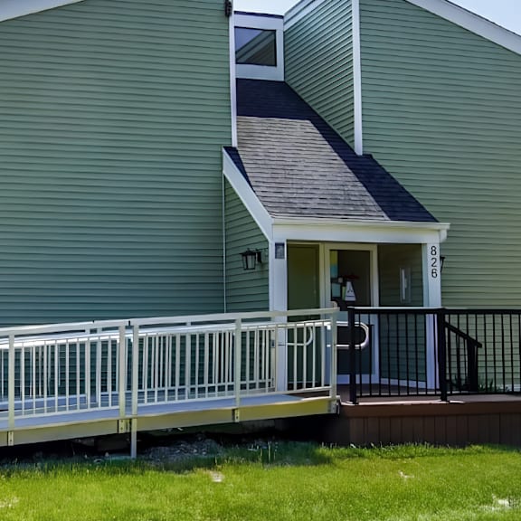 a green house with a white fence and a small porch.