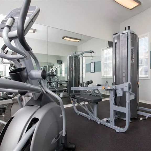 a gym with a lot of equipment and mirrors on the wall