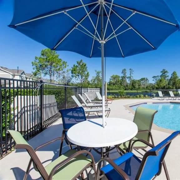 a table with a blue umbrella next to a pool