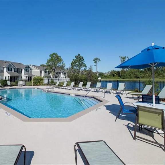 a resort style pool with chaise lounge chairs and umbrellas