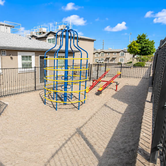 a playground with a blue and yellow structure and a red slide.
