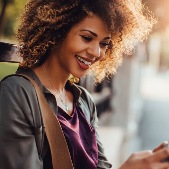 A woman with curly hair is looking at her phone.